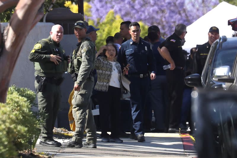 A woman reacts next to law enforcement officers after a deadly gunfire erupted at Geneva Presbyterian Church in Laguna Woods