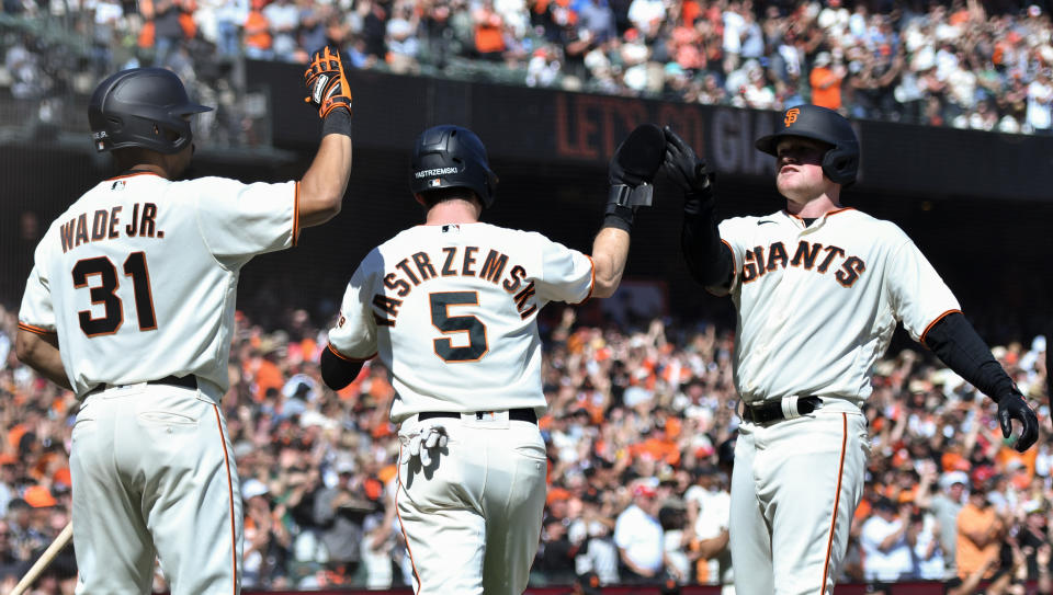 SAN FRANCISCO, CALIFORNIA - OCTOBER 03: LaMonte Wade Jr. #31, Mike Yastrzemski #5  and Logan Webb #62 of the San Francisco Giants score against the San Diego Padres in the 4th inning at Oracle Park on October 03, 2021 in San Francisco, California. (Photo by Brandon Vallance/Getty Images)