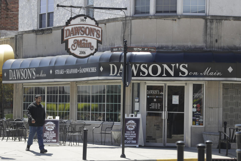 A man walks past Dawson's on Main, Tuesday, April 21, 2020, in Indianapolis. A.J. Foyt came to Indianapolis in 1958 a fearless rookie who rented a basement for $15 per week and slept on a cot not too far from the roar of the cars and crowds at Indianapolis Motor Speedway. Sometimes, he would walk to Main Street and join other drivers for breakfast at a drug store. That drug store where Foyt used to eat is still a restaurant, Dawson's on Main. The speedway is closed due to the coronavirus pandemic. (AP Photo/Darron Cummings)