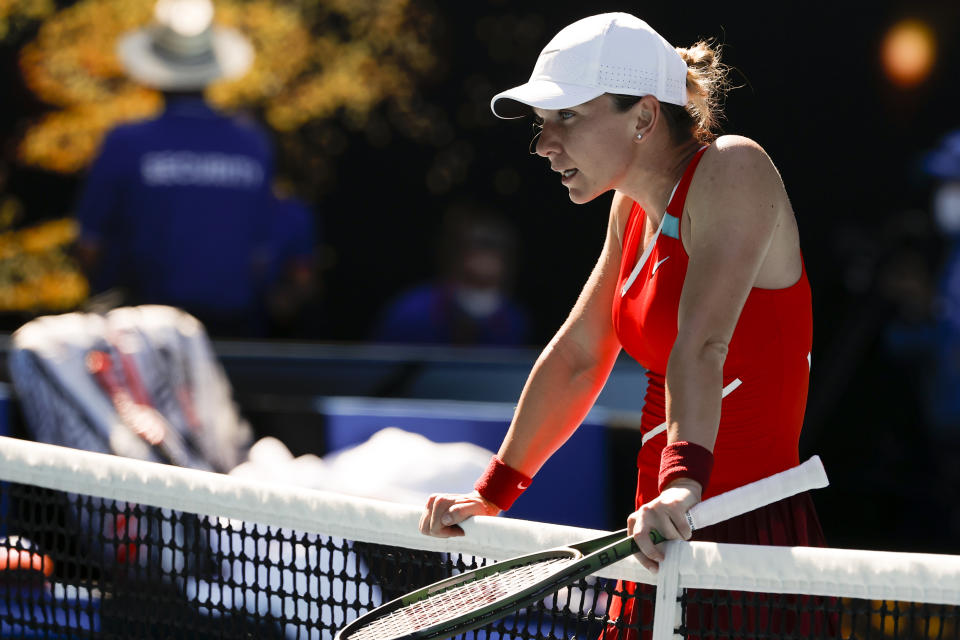 Simona Halep of Romania rests on the net following her fourth round loss to Alize Cornet of France at the Australian Open tennis championships in Melbourne, Australia, Monday, Jan. 24, 2022. (AP Photo/Tertius Pickard)