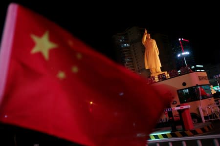 Chinese flag flutters near a statue of late Chinese chairman Mao Zedong at a train station in Dandong