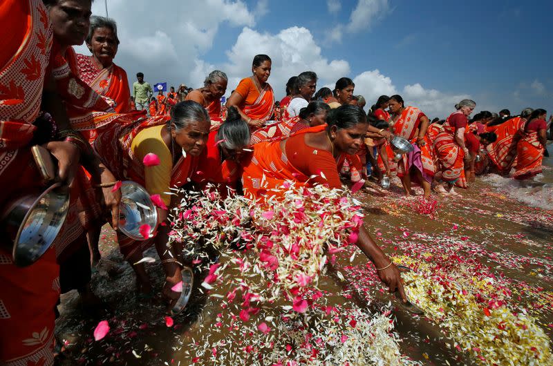 Women scatter flower petals in the waters of the Bay of Bengal during a prayer ceremony for the victims of the 2004 tsunami on the 15th anniversary of the disaster, in Chennai