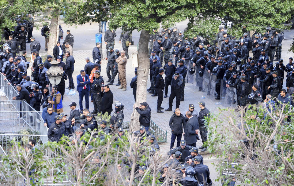 Security forces stand guard as Tunisians gather during a protest against Tunisian President Kais Saied in downtown Tunis, Tunisia, Saturday Jan. 14, 2023. Tunisians mark 12 years since Tunisian protesters unleashed Arab Spring uprisings around the region. The protest comes after disastrous parliamentary elections last month in which just 11% of voters cast ballots. It also comes as the country is going through a major economic crisis, with inflation and joblessness on the rise. (AP Photo/Hassene Dridi)