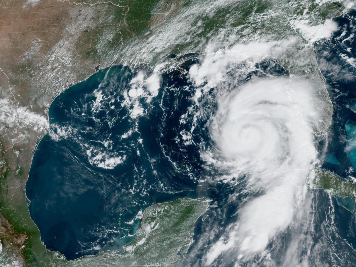 satellite image shows hurricane forming a cyclone of clouds above the gulf of mexico in between the yucatan peninsula and florida