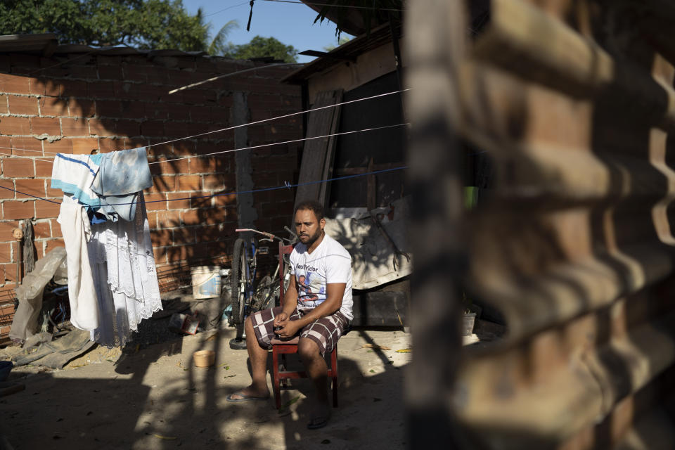In this June 20, 2019 photo, Jocely Rozario Junior, the father of Kaua, who was killed by a stray bullet, sits in his front yard at the Vila Alianca slum in Rio de Janeiro, Brazil. "My son wasn't an adult or a trafficker. He wasn't anything like that, but he lived with fear every time he saw the police," Rozário Junior said. "I can't be quiet because if so, Kaua would be just one more statistic." (AP Photo/Leo Correa)