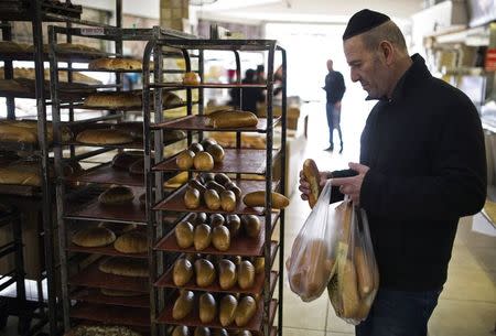 A customer checks loaves of bread at a bakery in the southern Israeli city of Ashkelon December 18, 2014. REUTERS/Amir Cohen