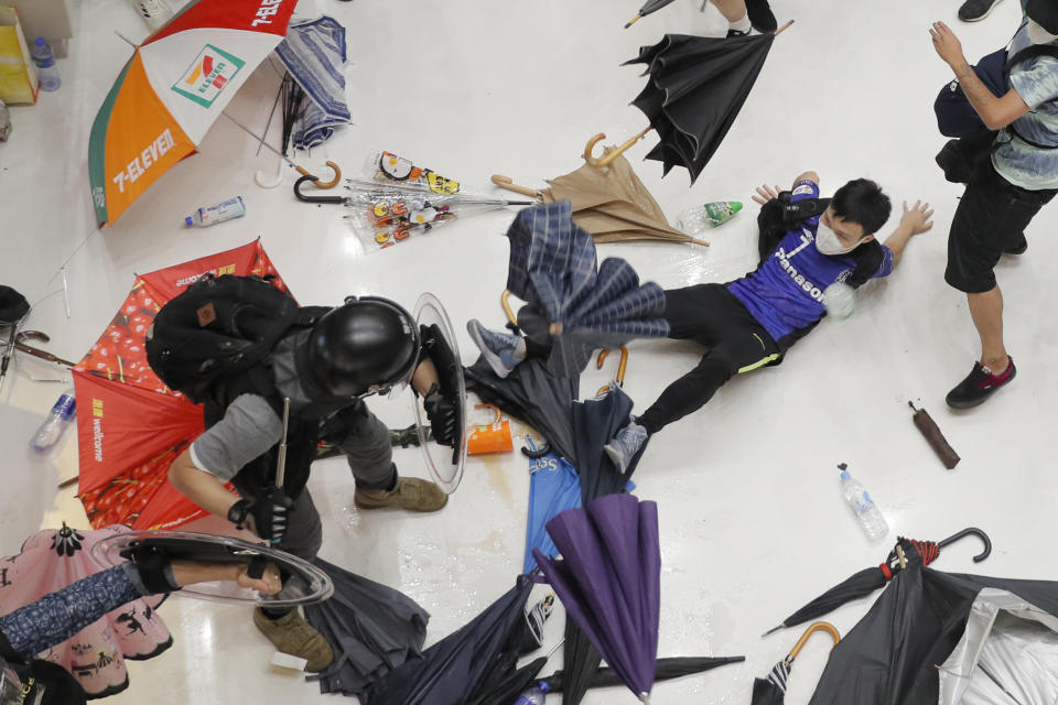 In this Sunday, July 14, 2019, photo, policemen scuffle with protesters inside a shopping mall in Sha Tin District in Hong Kong. Police in Hong Kong have fought with protesters as they broke up a demonstration by thousands of people demanding the resignation of the Chinese territory's chief executive and an investigation into complaints of police violence. (AP Photo/Kin Cheung)