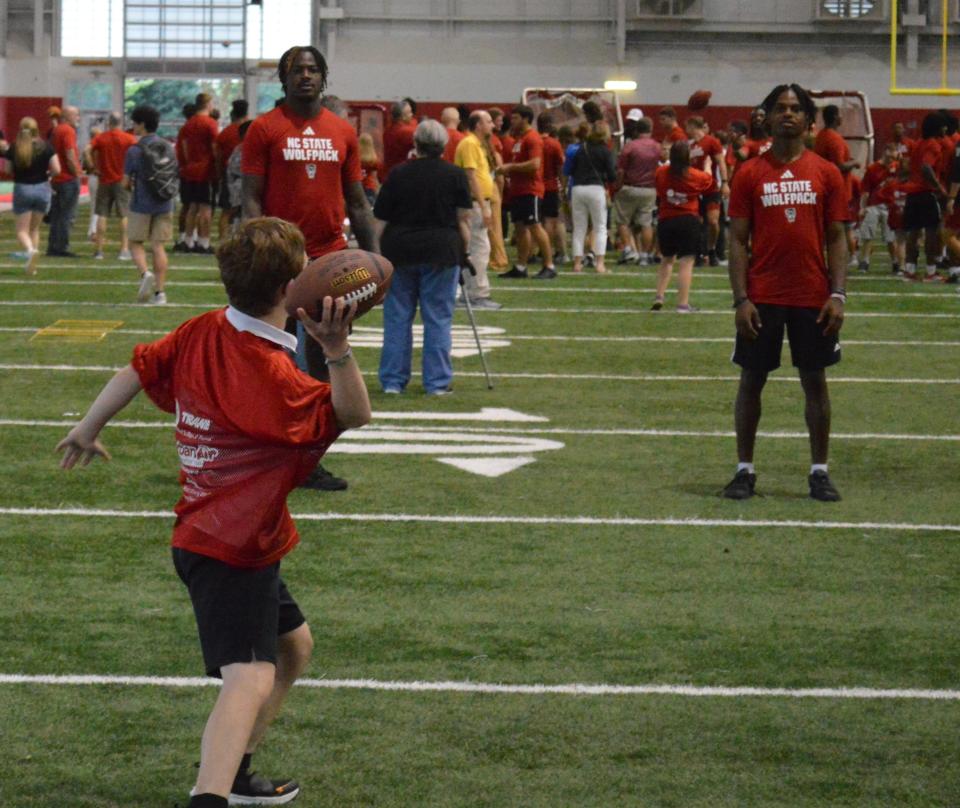 Lukas Steele, 15, throws a football with NC State's Shyheim Battle and Jamarion "JJ" Montford on Victory Day.