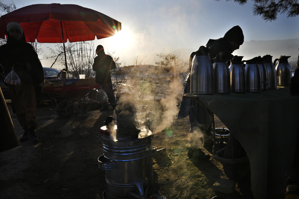 An Afghan tea maker, prepares his street stand near the frozen Qargha Lake, in Kabul, Afghanistan, in Kabul, Afghanistan, Friday, Feb. 11, 2022. (AP Photo/Hussein Malla)