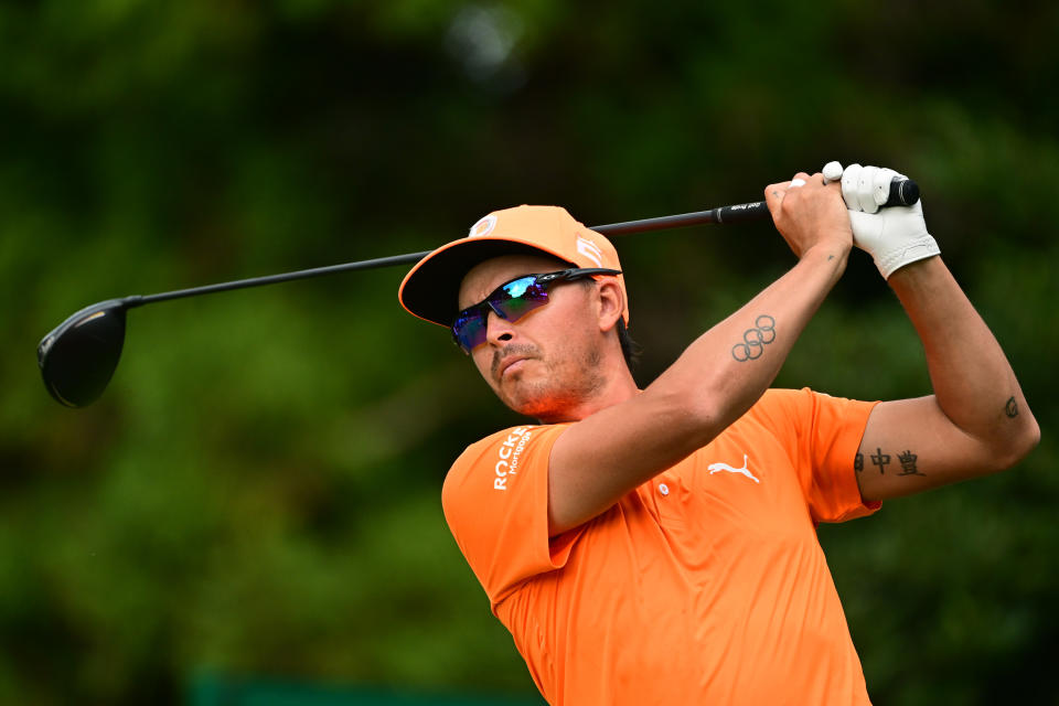 Fowler hits his tee shot in an orange shirt