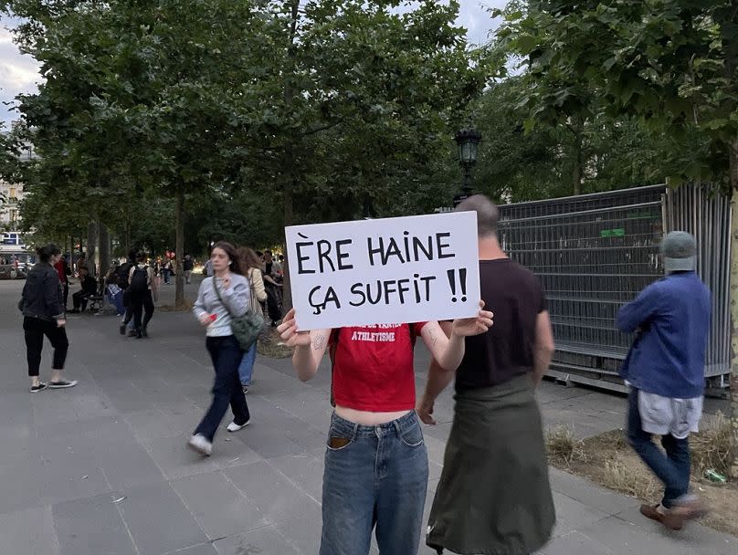 A protester with a sign that plays on the name of the far-right party, RN, to say "era of hatred, that's enough".