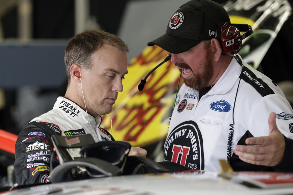 Kevin Harvick, left, speaks with a crew member in the garage during practice Sunday's NASCAR Cup Series auto race at Charlotte Motor Speedway in Concord, N.C., Saturday, Sept. 28, 2019. (AP Photo/Gerry Broome)