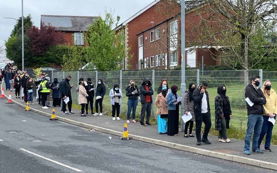 People queue for the vaccination centre at the Essa Academy in Bolton. - PA
