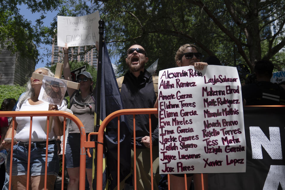 A protester holds a sign bearing the names of this week's elementary school shooting victims during a rally against the National Rifle Association's annual meeting outside the George R. Brown Convention Center in Houston, Friday, May 27, 2022. (AP Photo/Jae C. Hong)