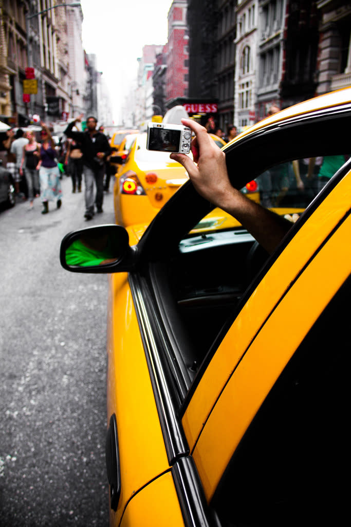 A cab driver photographs Occupy Wall Street marchers spilling into the street.