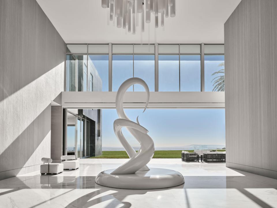 A rotating white sculpture titled Unity by Mike Fields anchors the home’s foyer, which also features a custom white glass Murano chandelier.
