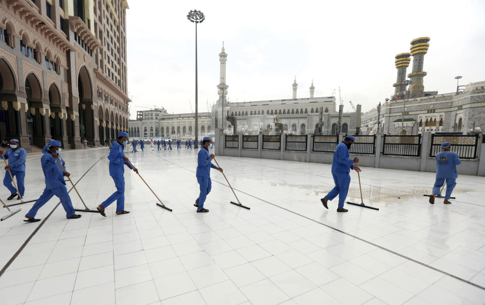 Workers disinfect the ground outside the Grand Mosque, over fears of the new coronavirus, at the Muslim holy city of Mecca, Saudi Arabia, Monday, July 27, 2020. Anywhere from 1,000 to 10,000 pilgrims will be allowed to perform the annual hajj pilgrimage this year due to the coronavirus pandemic. (AP Photo)