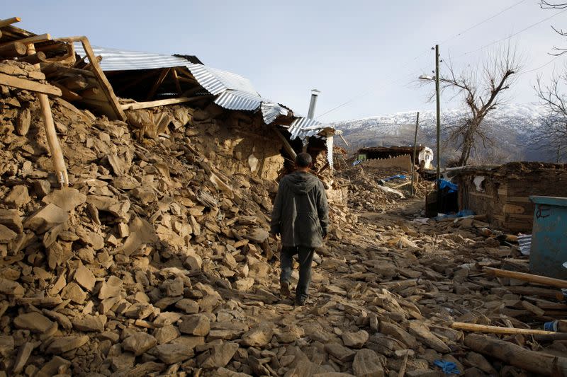 A man walks among debris, after an earthquake in Cevrimtas