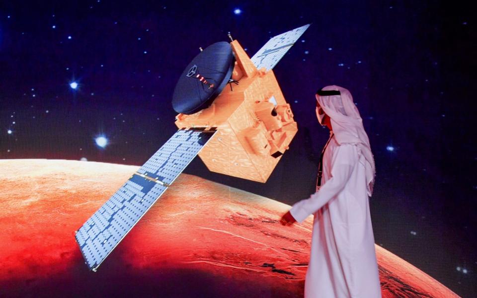 An Emirati walks past a screen displaying the "Hope" Mars probe at the Mohammed Bin Rashid Space Centre in Dubai - GIUSEPPE CACACE /AFP