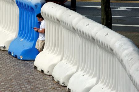 A passerby walks past a barricade near the hotel where Chinese President Xi Jinping will stay, five days before the territory celebrates the 20th anniversary of its handover to Chinese rule, in Hong Kong, China June 26, 2017. REUTERS/Bobby Yip