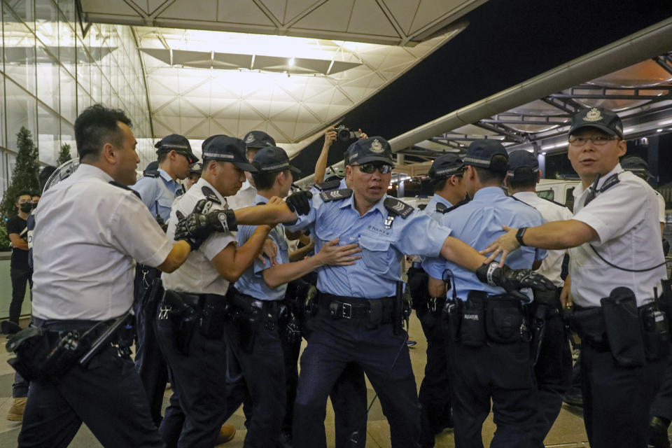 Policemen pull back after reacting with protesters outside the Airport in Hong Kong, Tuesday, Aug. 13, 2019. Riot police clashed with pro-democracy protesters at Hong Kong's airport late Tuesday night, a chaotic end to a second day of demonstrations that caused mass flight cancellations at the Chinese city's busy transport hub. (AP Photo/Vincent Yu)