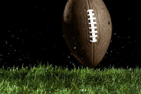A football on turf, black background.