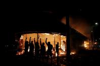 Protesters are seen outside of a liquor store on fire near the Minneapolis Police third precinct as demonstrations continue in Minneapolis