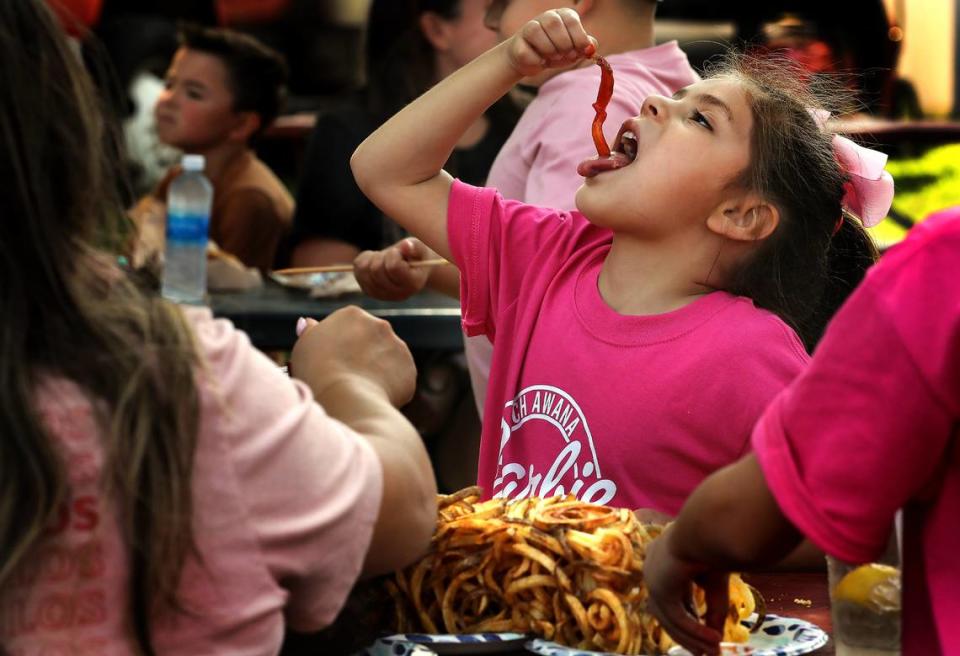 Catalina Ramirez, 6, enjoys an extra long french fry covered in ketchup from a basket of curly fries she was sharing with her siblings and parents while at the Benton Franklin Fair & Rodeo at the fairgrounds in Kennewick. Her parents are Valerie & Roman Ramirez of Pasco.