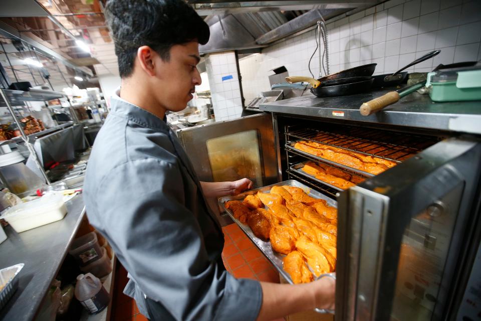Suyash Patil loads saffron chicken into an oven at the newly opened Saffron by the Sea in Fairhaven.