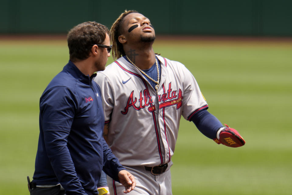 Ronald Acuña Jr. walks off the field with a coach after tearing his anterior cruciate ligament.  (AP Photo/Jane J. Pushkar)