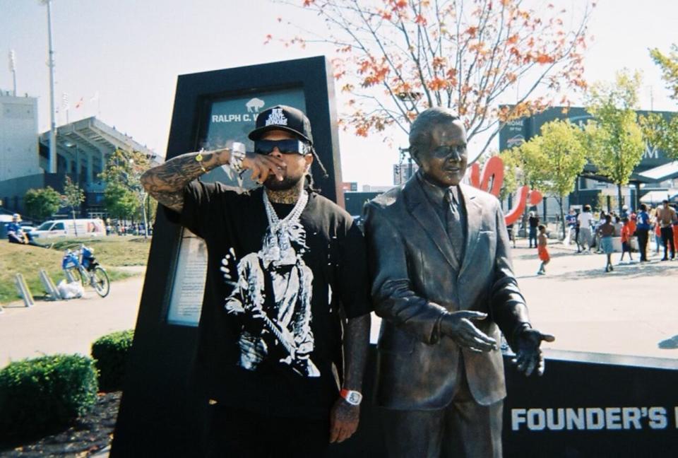 Westside Gunn poses next to a statue of Ralph C. Wilson, Jr. at Founder’s Plaza, New Era Field in Orchard Park, N.Y. (Photo credit: ProlificKid)