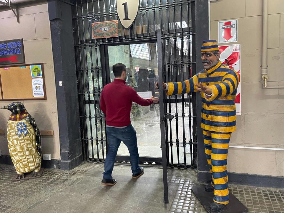 A tourist walks through a barred doorway in a prison museum.