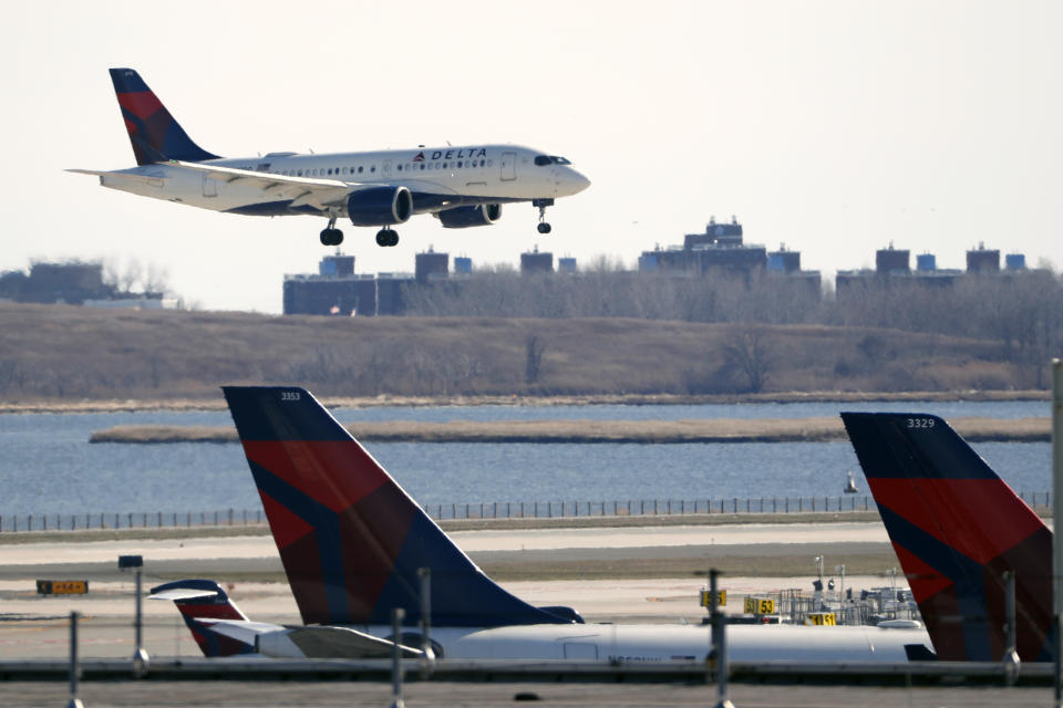 FILE - A Delta Airlines jet lands at John F. Kennedy International Airpor as two other Delta planes are shown at the terminal, Saturday, March 14, 2020, in New York. Delta Air Lines has suspended its partnership with Russian national airline Aeroflot following Russia's invasion of Ukraine. Atlanta-based Delta on Friday, Feb. 25, 2022, said the decision was effective immediately. (AP Photo/Kathy Willens, File)