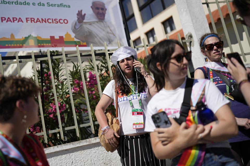 Victoria, center, from Spain, speaks on the phone outside the Sao Vicente de Paulo Parish Social Center, together with representatives of Dignity USA, a group of LGBTQ+ Catholics, after Pope Francis visited it in the Serafina neighbourhood of Lisbon, Friday, Aug. 4, 2023. In Lisbon, Francis has emphasized the inclusive message of the church that he has championed throughout his 10-year papacy, telling the World Youth Day opening ceremony that "in the church, there is room for everyone" and leading the crowd of a half-million people in a chant of "everyone, everyone, everyone." That message has resonated in particular with LGBTQ+ Catholics, who have long felt ostracized by a church that considers homosexual activity "intrinsically disordered." (AP Photo/Armando Franca)