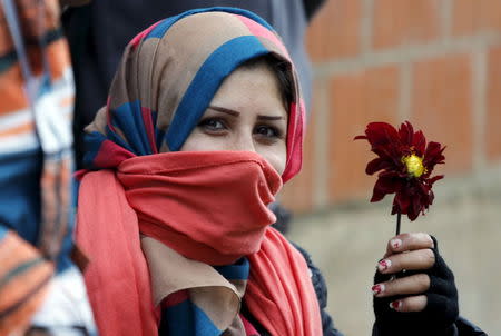 A migrant holds a flower as she waits for buses at Miratovac village, Serbia October 24, 2015. REUTERS/Ognen Teofilovski