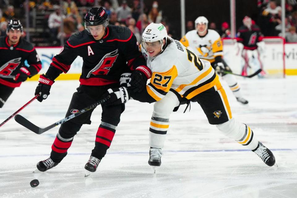 Nov 18, 2023; Raleigh, North Carolina, USA; Carolina Hurricanes center Sebastian Aho (20) tries to control the puck against Pittsburgh Penguins defenseman Ryan Graves (27) during the first period at PNC Arena. Mandatory Credit: James Guillory-USA TODAY Sports James Guillory/James Guillory-USA TODAY Sports