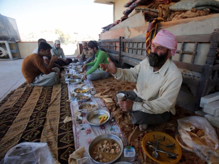 Workers from the minority Yazidi sect, eat during a break from rebuilding a Yazidi shrine which was destroyed by Islamic State, in Bashiqa, a town near Mosul, Iraq August 8, 2017. Picture taken August 8, 2017.  REUTERS/Khalid al Mousily