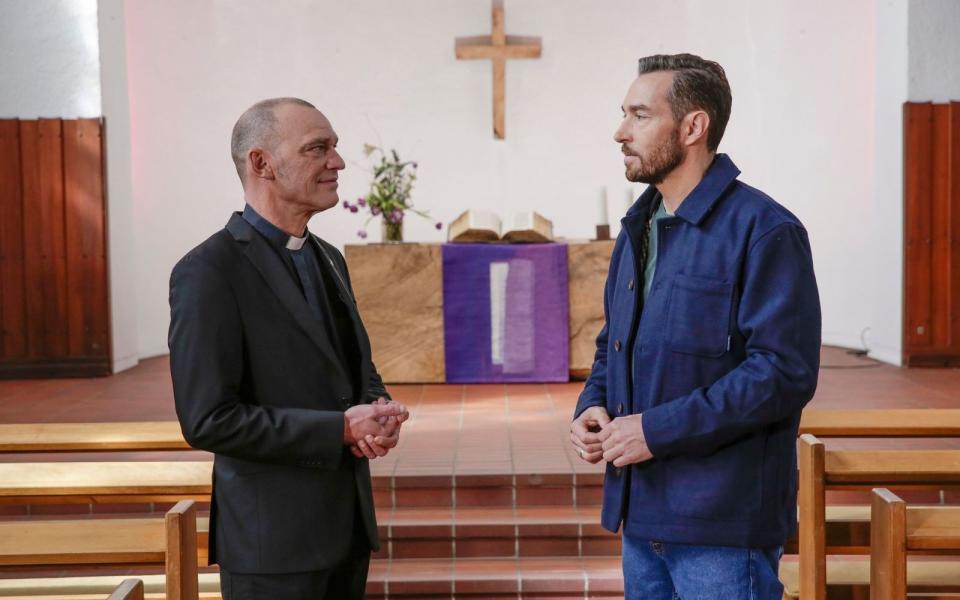 Ein Pfarrer berichtet Sven Voss (rechts) von den Selbstzweifeln und Seelenqualen, die die Tochter der erwürgten Mutter durchleiden musste. (Bild: ZDF / Saskia Pavek)