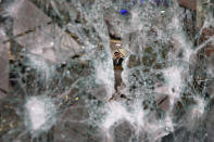 FILE - In this Jan. 15, 2020 file photo, a bank employee is seen through the broken facade of a branch of the Bank of Beirut that was smashed by anti-government protesters in Beirut, Lebanon. Riad Salameh, Lebanon’s long-serving central bank governor, was touted as the guardian of Lebanon’s monetary stability as he steered the tiny country's finances through post-war recovery and various bouts of unrest for nearly three decades. Now he is being called a “thief” by some protesters, who accuse him of being part of the ruling elite whose corruption and mismanagement has driven the country to the edge of bankruptcy. (AP Photo/Bilal Hussein, File)