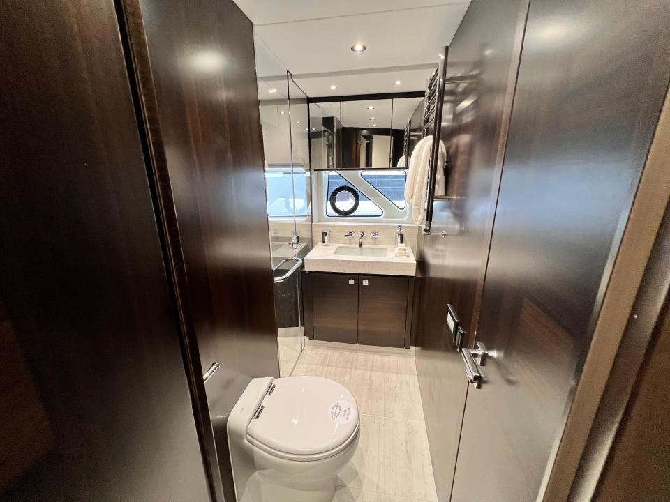 A bathroom onboard the Sunseeker 76, with wooden paneling and a marble countertop sink.