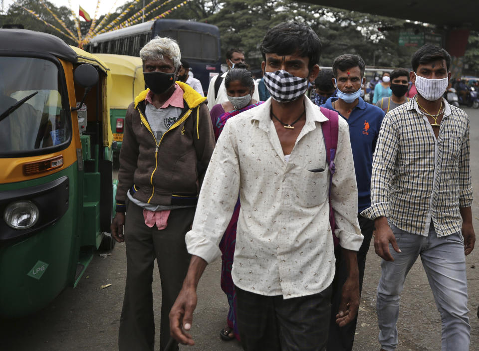 Indian commuters wearing face mask as a precaution against the coronavirus arrive at a bus station in Bengaluru, India, Tuesday, Jan. 5, 2021. India authorized two COVID-19 vaccines on Sunday, paving the way for a huge inoculation program to stem the coronavirus pandemic in the world's second most populous country. (AP Photo/Aijaz Rahi)