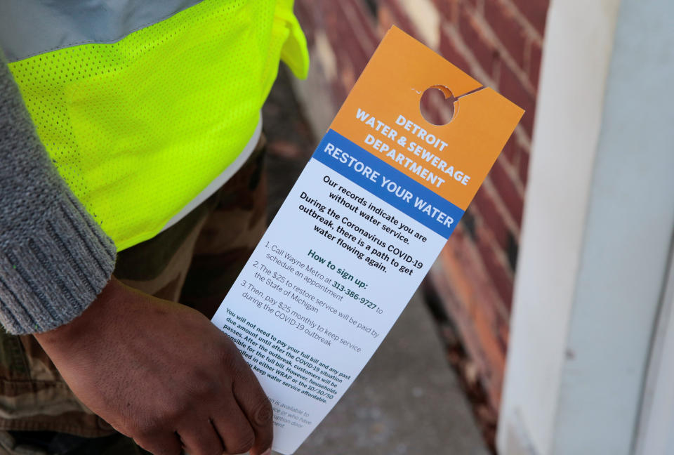 Image: Contract worker Vaughn Harrington holds notices by the Detroit Water and Sewerage Department to inform residents how to restore water service in response to the coronavirus outbreak in Detroit (Rebecca Cook / Reuters)