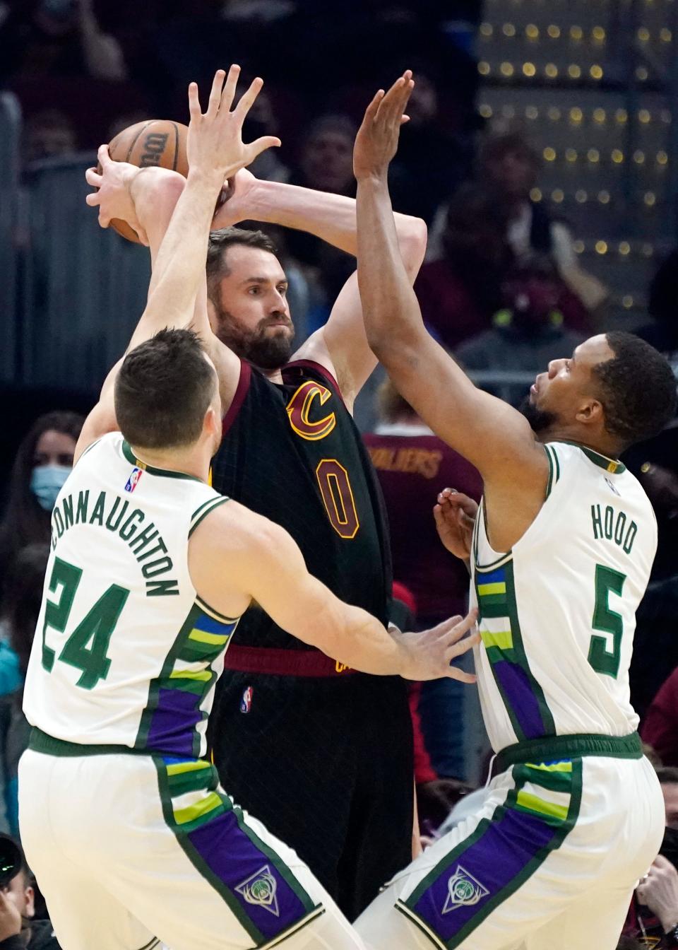 Cavaliers forward Kevin Love, center, passes as Milwaukee Bucks' Pat Connaughton, left, and Rodney Hood defend in the first half of the Cavs' 115-99 win Wednesday night. [Tony Dejak/Associated Press]