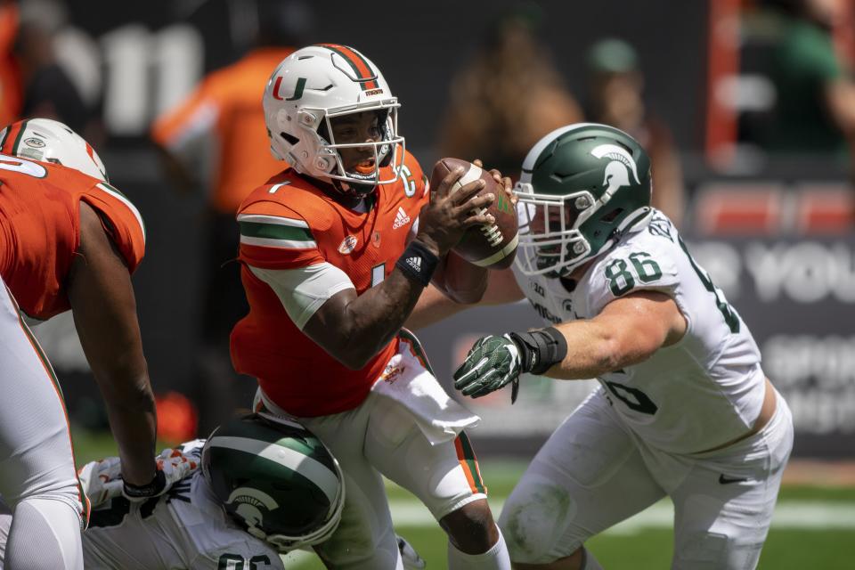 Miami quarterback D'Eriq King (1) runs with the ball under pressure from Michigan State defensive end Drew Beesley (86) during an NCAA football game on Saturday, Sept 18, 2021 in Miami Gardens, Fla. (AP Photo/Doug Murray)