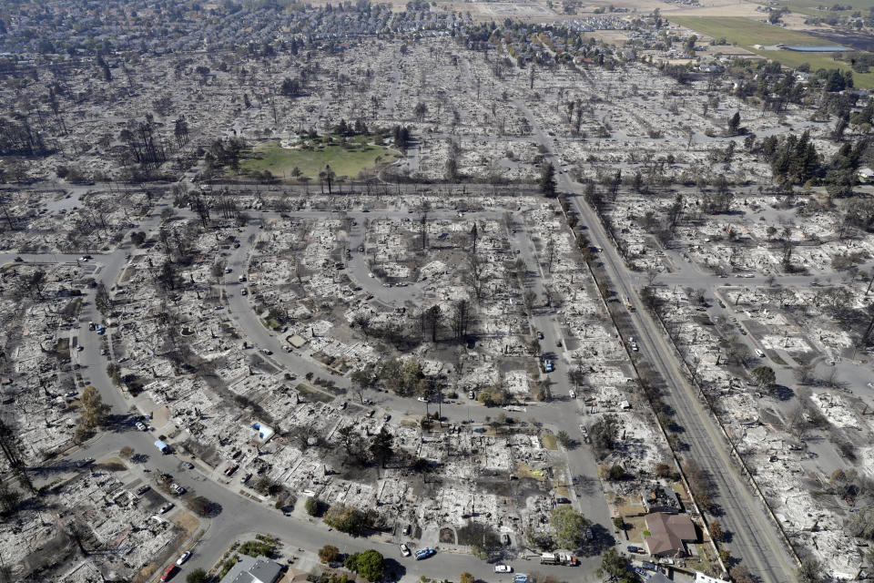 FILE - In this Oct. 14, 2017 file photo, an aerial view shows the devastation of the Coffey Park neighborhood after a wildfire swept through it in Santa Rosa, Calif. As California counties face the prospect of increased utility power shut-off meant to prevent wildfires, counties with more resources are adapting much more easily to the challenge than poorer ones. (AP Photo/Marcio Jose Sanchez, File)