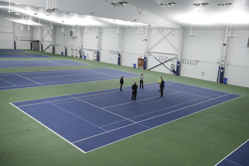 New York City Mayor Bill de Blasio, right, meets with officials on the practice courts at the USTA Indoor Training Center where a 350-bed temporary hospital will be built Tuesday, March 31, 2020, in New York. The new coronavirus causes mild or moderate symptoms for most people, but for some, especially older adults and people with existing health problems, it can cause more severe illness or death. (AP Photo/Frank Franklin II)