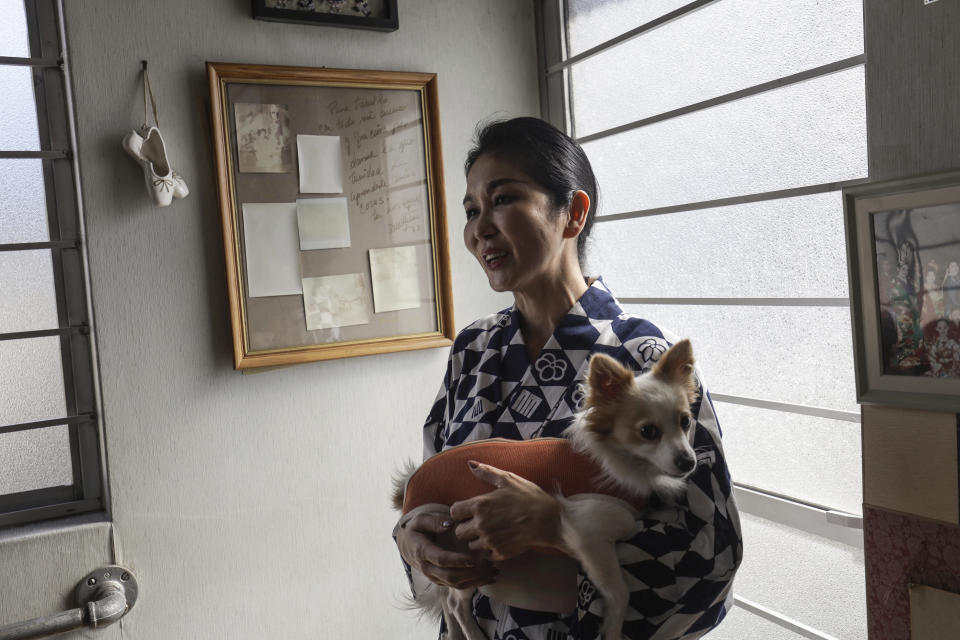 Professor Naoko Kihara, who has practiced Hanayagi-style dance for over two decades, stands in her studio cradling her dog Inosuke, during an interview in Mexico City, Wednesday, Nov. 22, 2023. Kihara is eager to share her Japanese legacy with audiences in her current hometown. (AP Photo/Ginnette Riquelme)