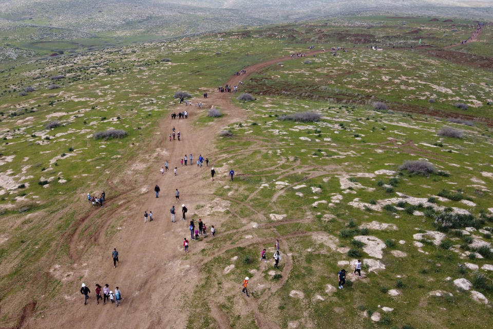 In this Friday, Feb. 21, 2020 photo, people walk on the hills in the West Bank during the Jordan Valley parade, in Jordan Valley. Israel's Prime Minister Benjamin Netanyahu is eager to court the votes of the country's influential West Bank settlers in critical elections next month. President's Donald Trump's Mideast plan seemed to be the key to ramping up their support. The plan envisions Israel's eventual annexation of its scores of West Bank settlements — a long time settler dream. But in the weeks since it was unveiled, Netanyahu has stumbled over his promises to quickly carry out the annexation, sparking verbal attacks from settler leaders. (AP Photo/Ariel Schalit)