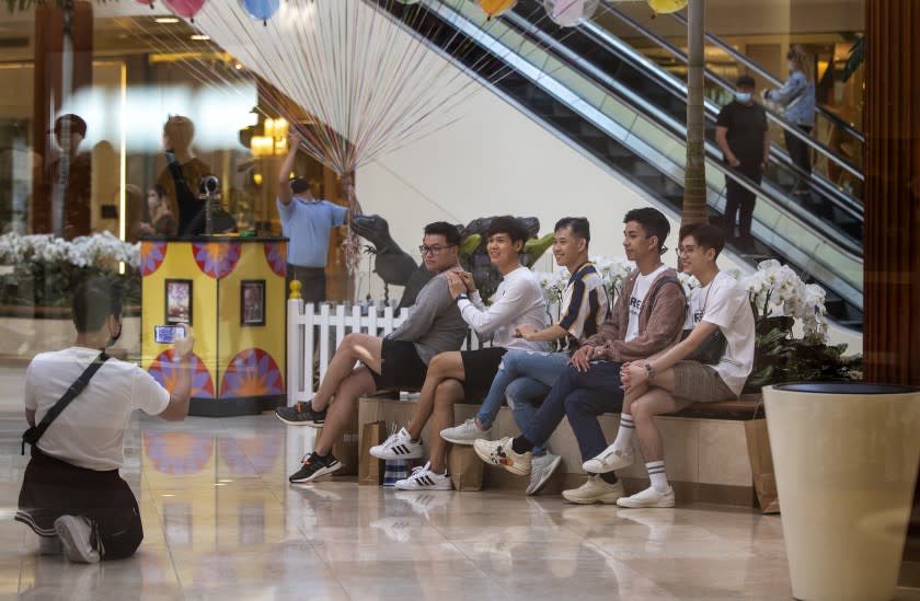 COSTA MESA, CA - MAY 13, 2021: A group of shoppers take off their masks to pose for a photo across from the carousel inside South Coast Plaza on May 13, 2021 in Costa Mesa, California. Even though, the CDC announced Thursday that masked are no longer required for fully vaccinated people, the mall is still requiring masks indoors.(Gina Ferazzi / Los Angeles Times)