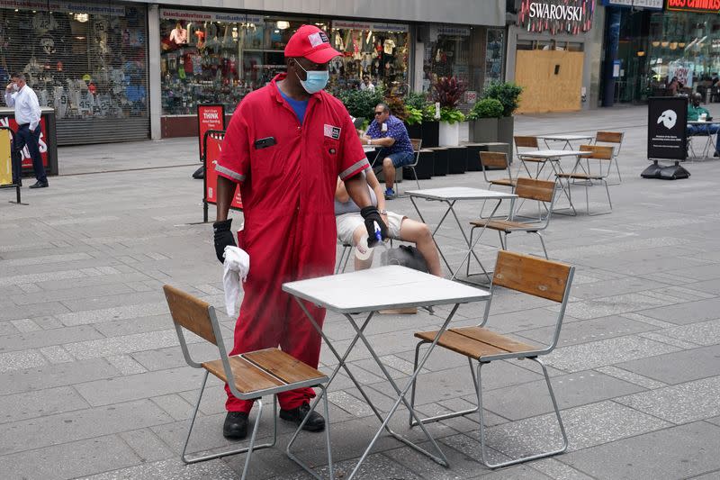 A worker cleans and disinfects a table in Times Square in the Manhattan borough of New York City